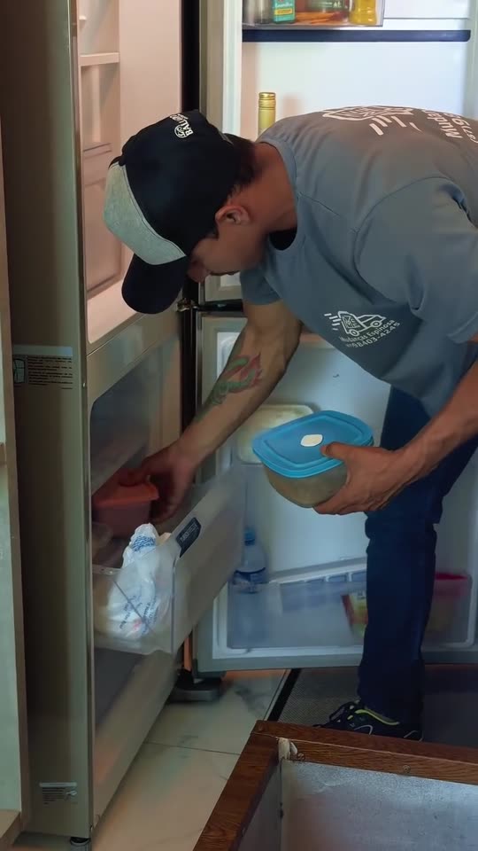 Carregador esvaziando e organizando os alimentos da geladeira antes da mudança